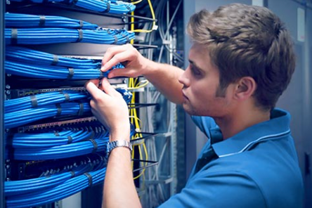 Man working with blue network cables in a server room.