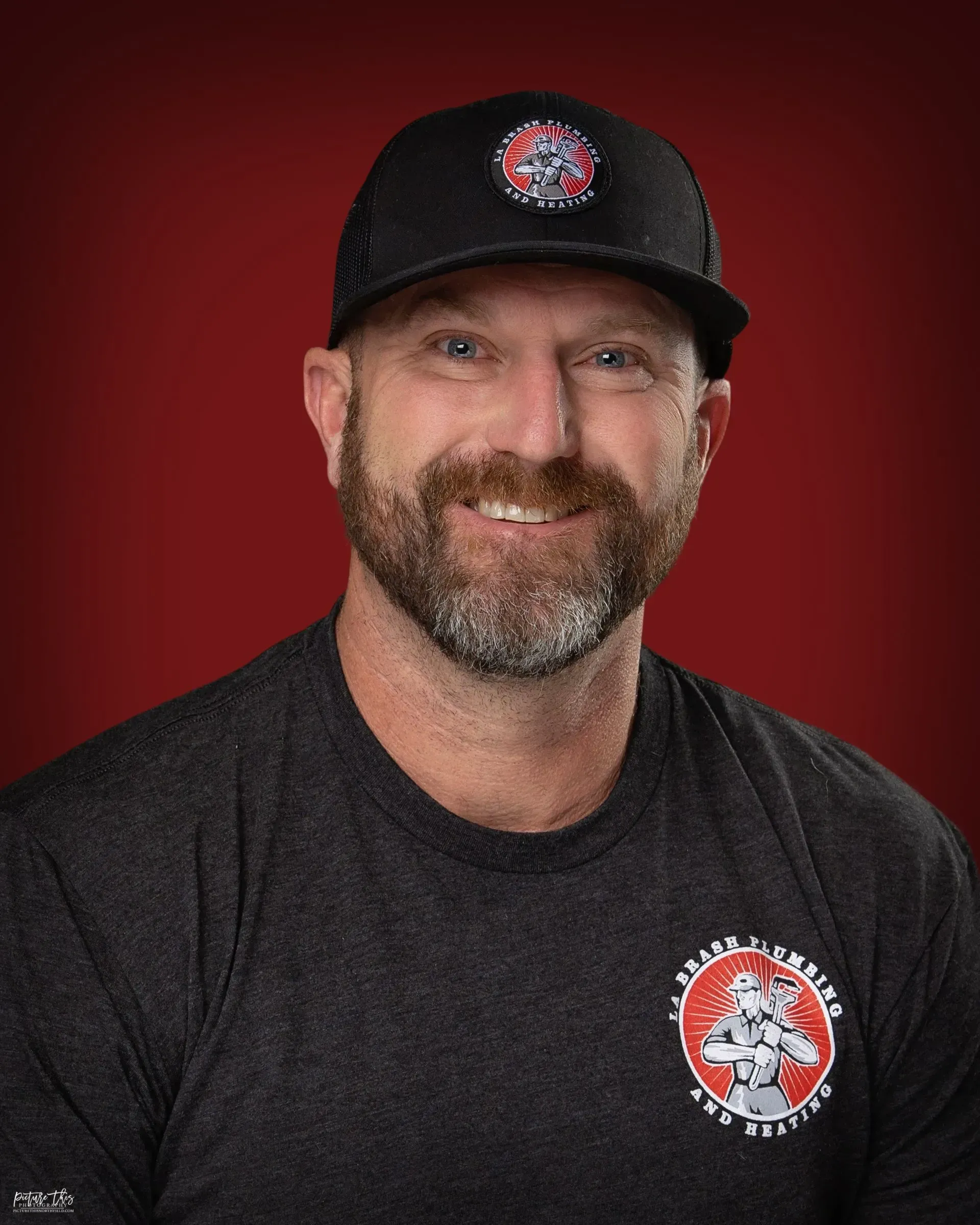A man with a beard and a hat is smiling for the camera.