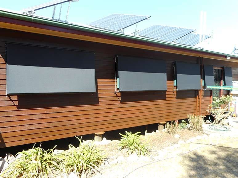 Brown Wooden House With Black Sunshades and Solar Panels — Toowoomba Shade & Canvas in Harristown, QLD