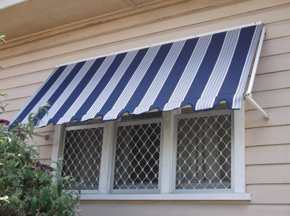 Blue and white striped awning shading a window with security grilles.
