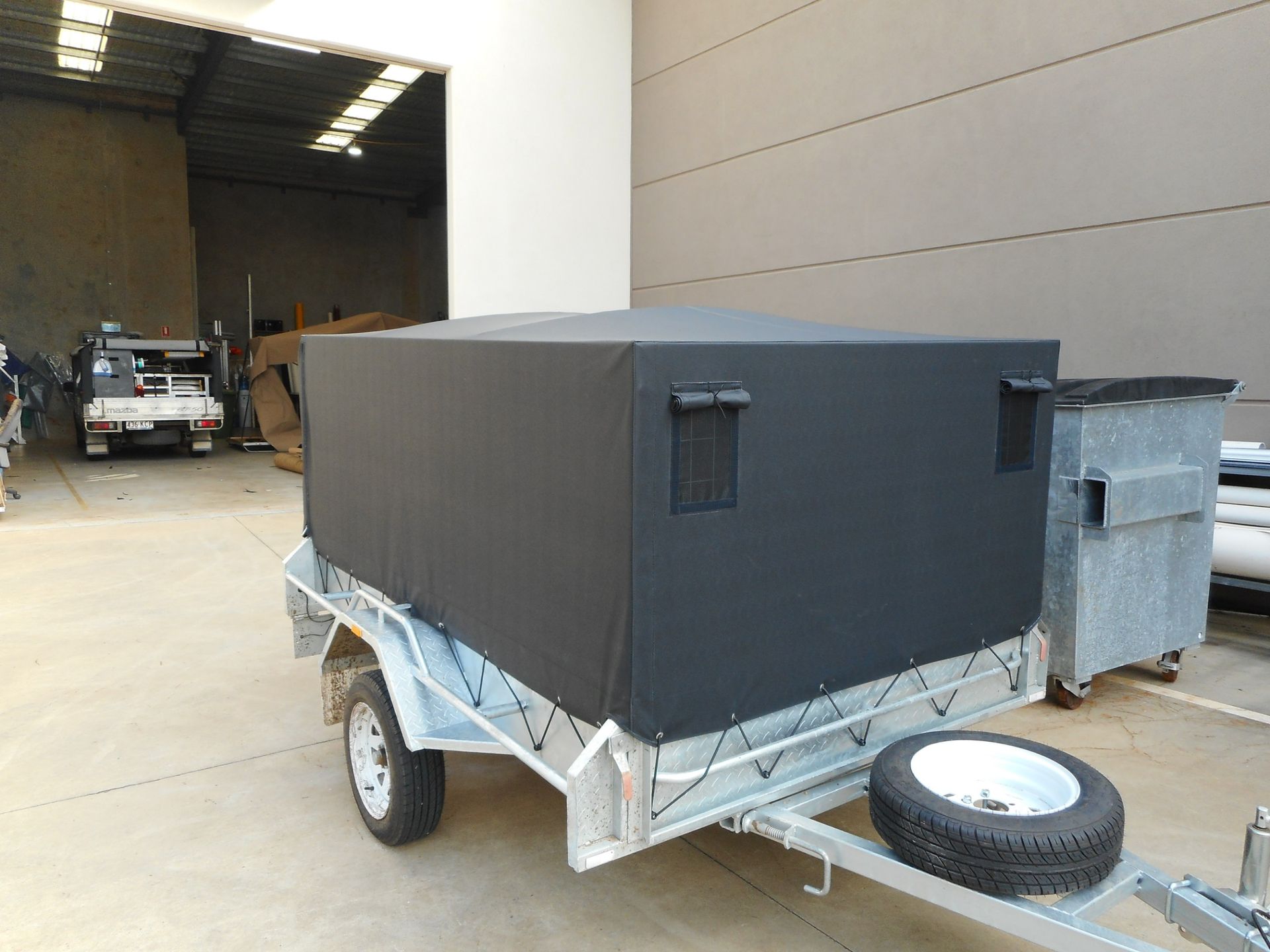 A Black Tarp-covered Trailer Sits in a Warehouse — Toowoomba Shade & Canvas in Harristown, QLD