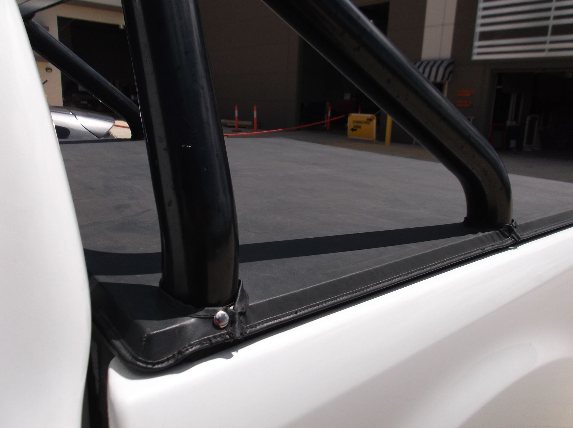 Close-up of a White Truck Bed With a Black Roll Bar and a Tonneau Cover — Toowoomba Shade & Canvas in Harristown, QLD