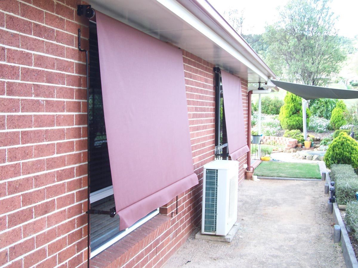 Red awning over a brick building's window, with an air conditioning unit below.