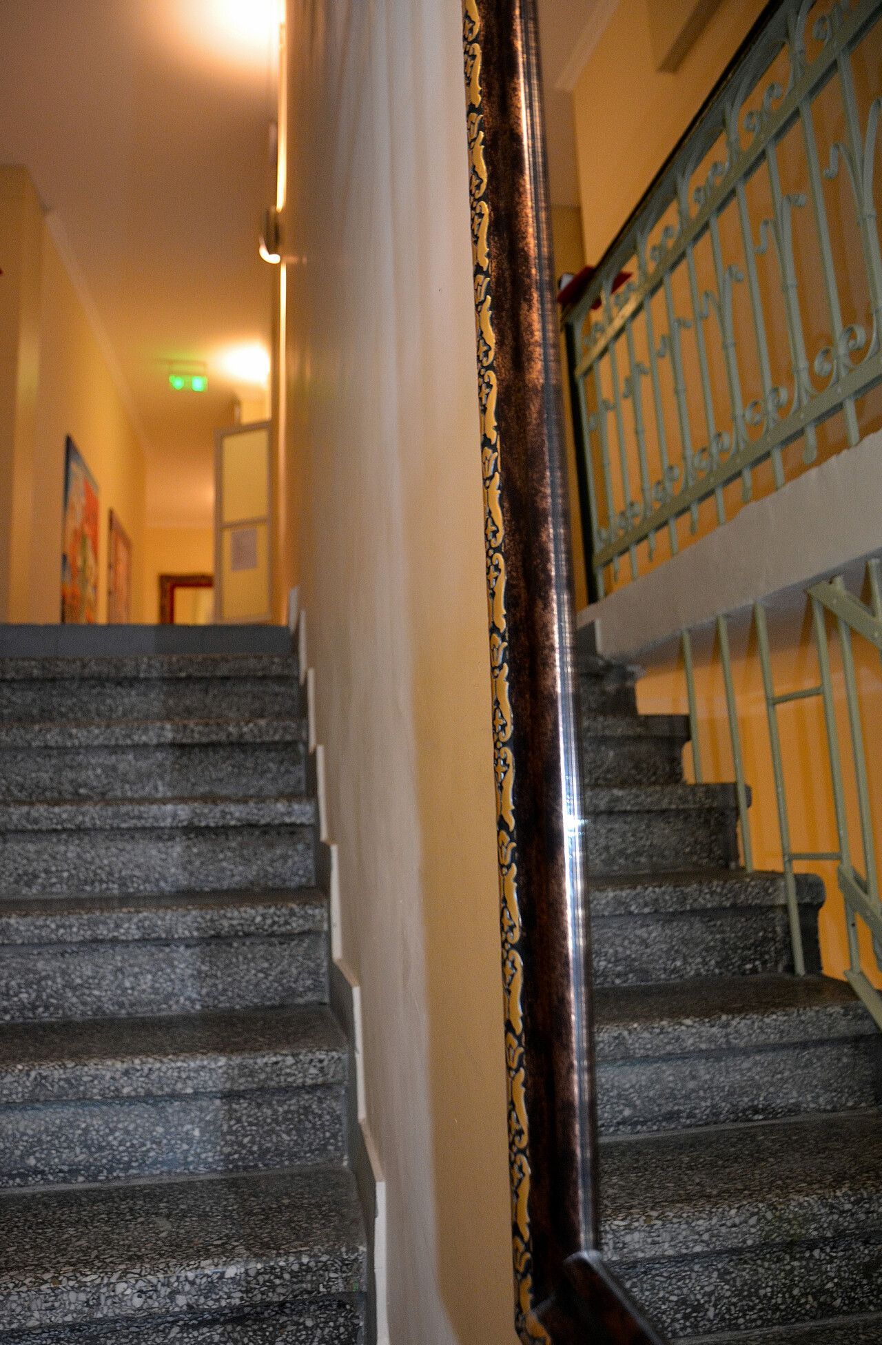 Μια σκάλα με γκρίζα σκαλοπάτια με στίγματα, δίπλα σε έναν μακρύ, κάθετο επιτοίχιο καθρέφτη που αντανακλούσε μια αντίστοιχη σκάλα.