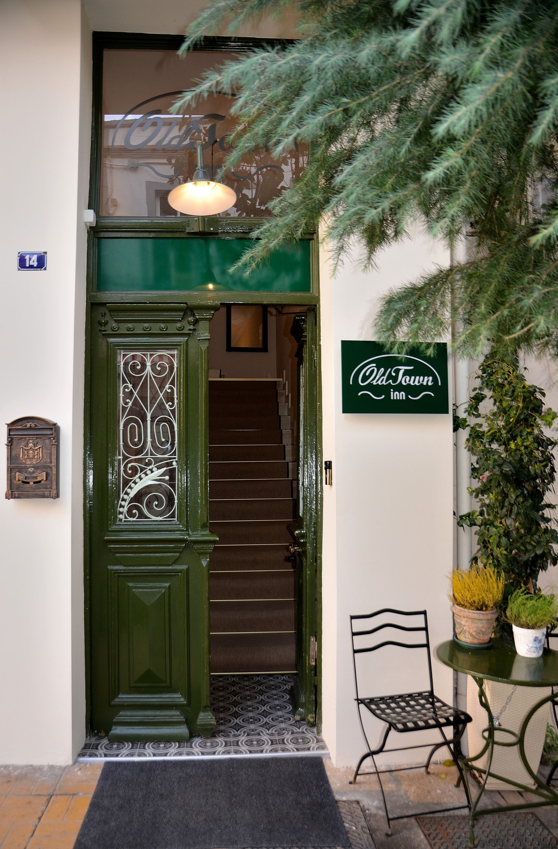 Μια είσοδος με μια σκούρα πράσινη πόρτα, μια πινακίδα που έγραφε «Παλιά Πόλη» και ένα μικρό τραπέζι με καρέκλα μπιστρό σε ένα πέτρινο πεζοδρόμιο.