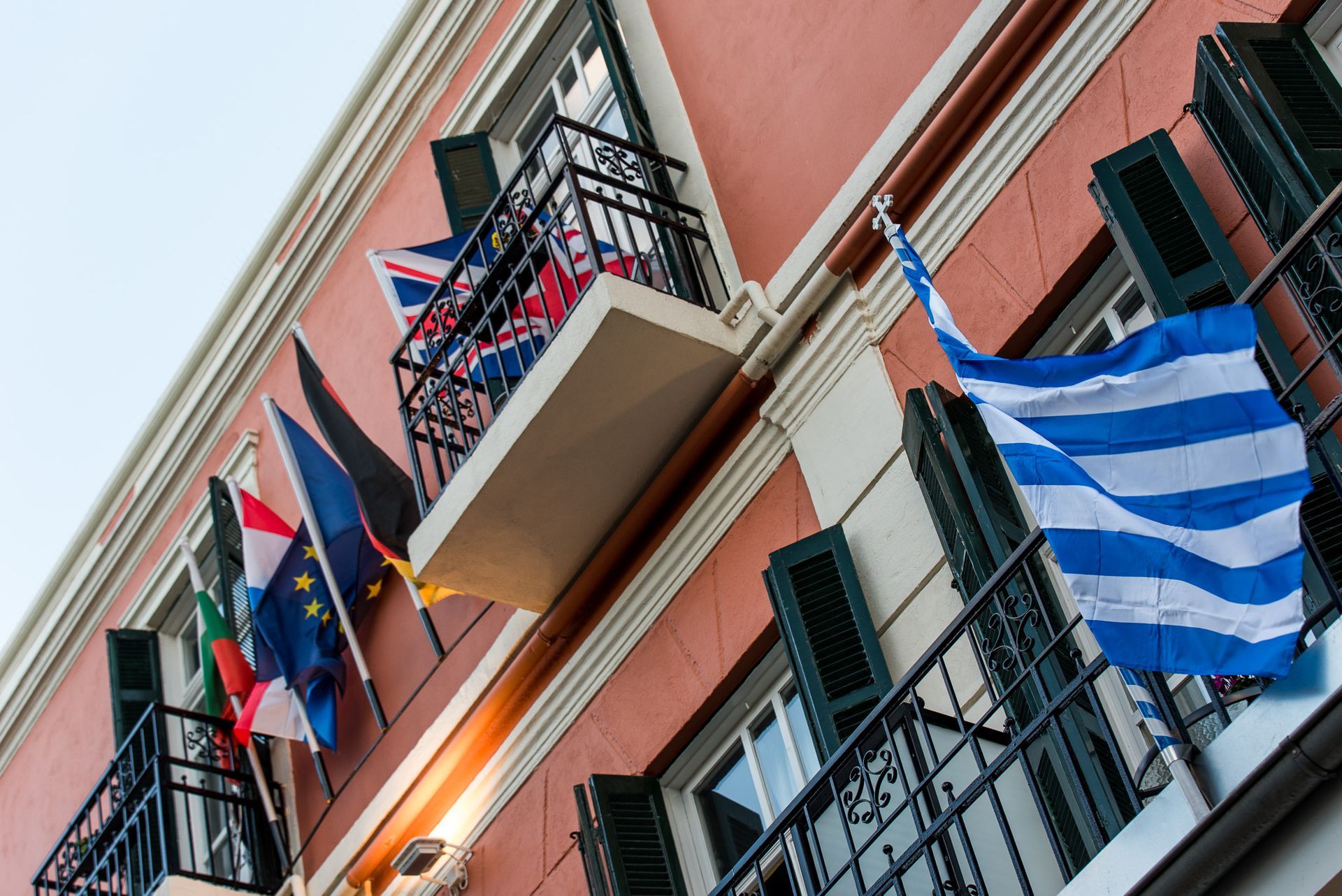 Μια θέα προς ένα πολυώροφο κτίριο με αρκετές εθνικές σημαίες να κρέμονται από μπαλκόνια.