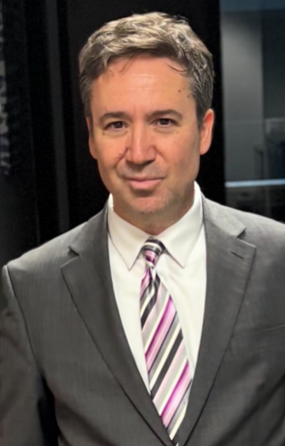 A judge 's gavel is sitting on a wooden table in front of a man using a laptop.