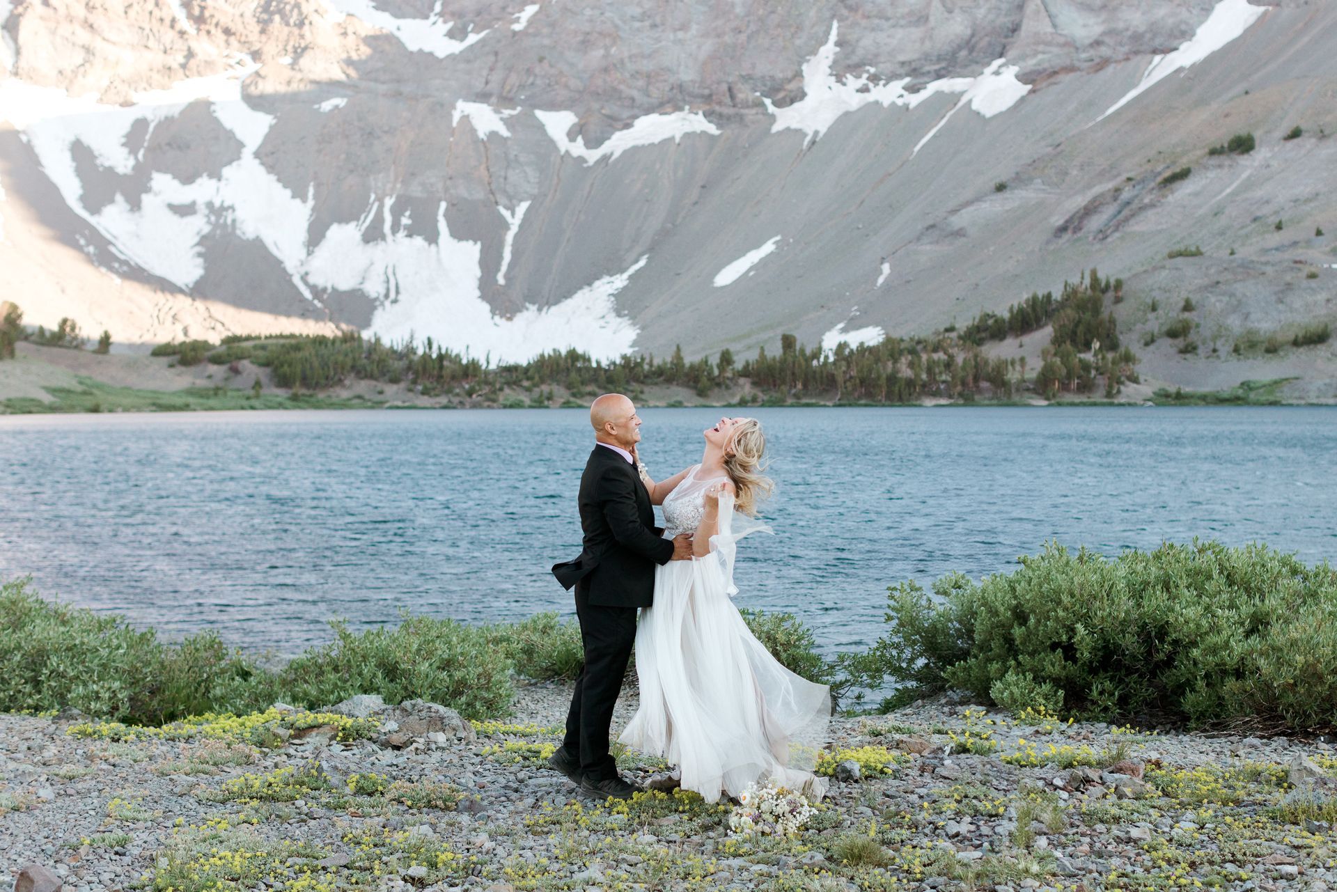 A bride and groom are laying on the ground on their wedding day.