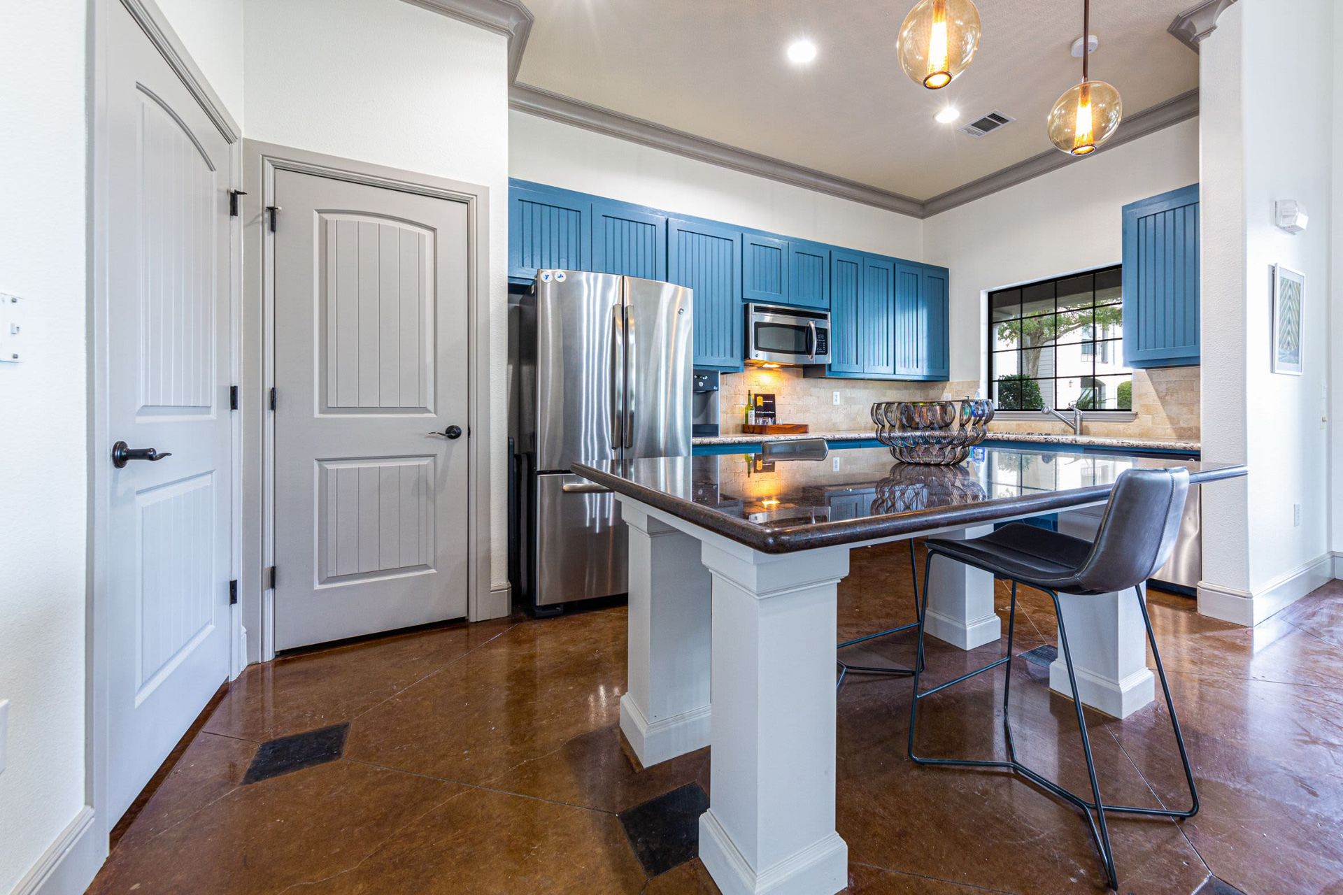 A kitchen with blue cabinets, stainless steel appliances, granite countertops, and a large island at Marquis Grand Lakes in Richmond, TX.