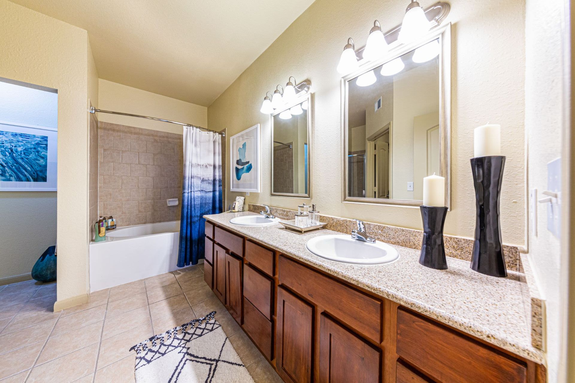 A bathroom with two sinks, two mirrors, and a bathtub at Marquis Grand Lakes in Richmond, TX.