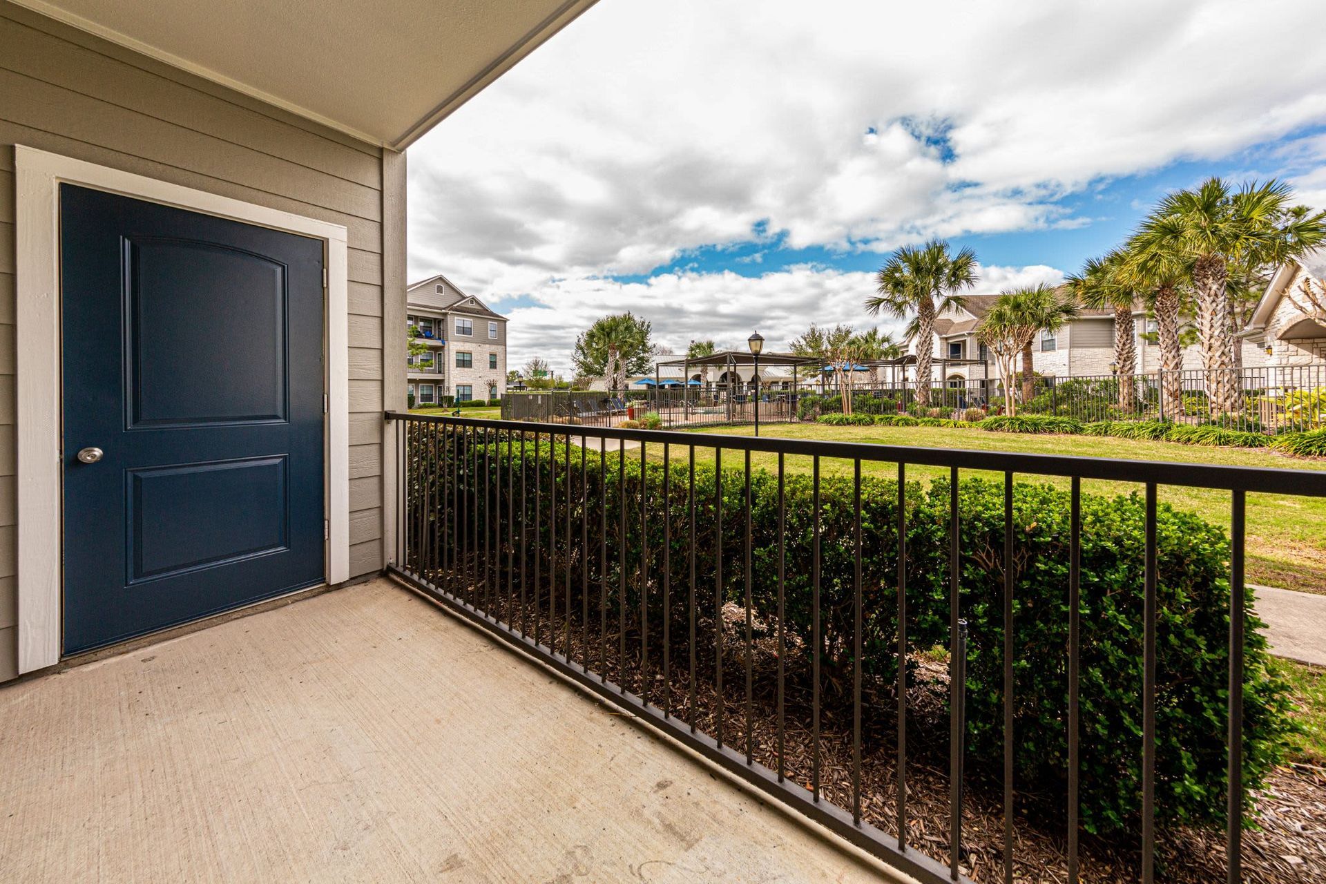 A balcony with a blue door and a metal railing at Marquis Grand Lakes in Richmond, TX.