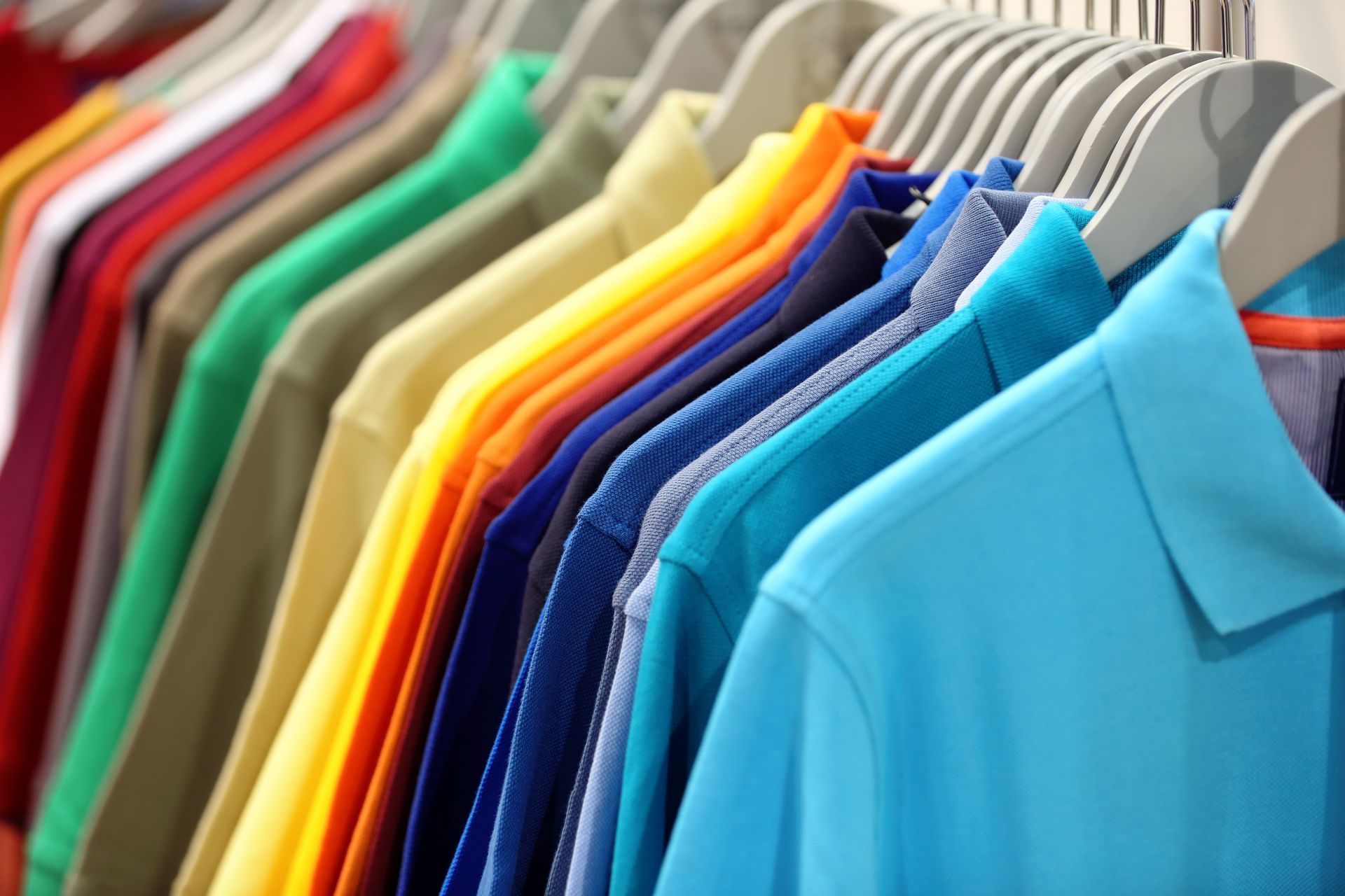Row of colorful polo shirts hanging on a clothing rack.