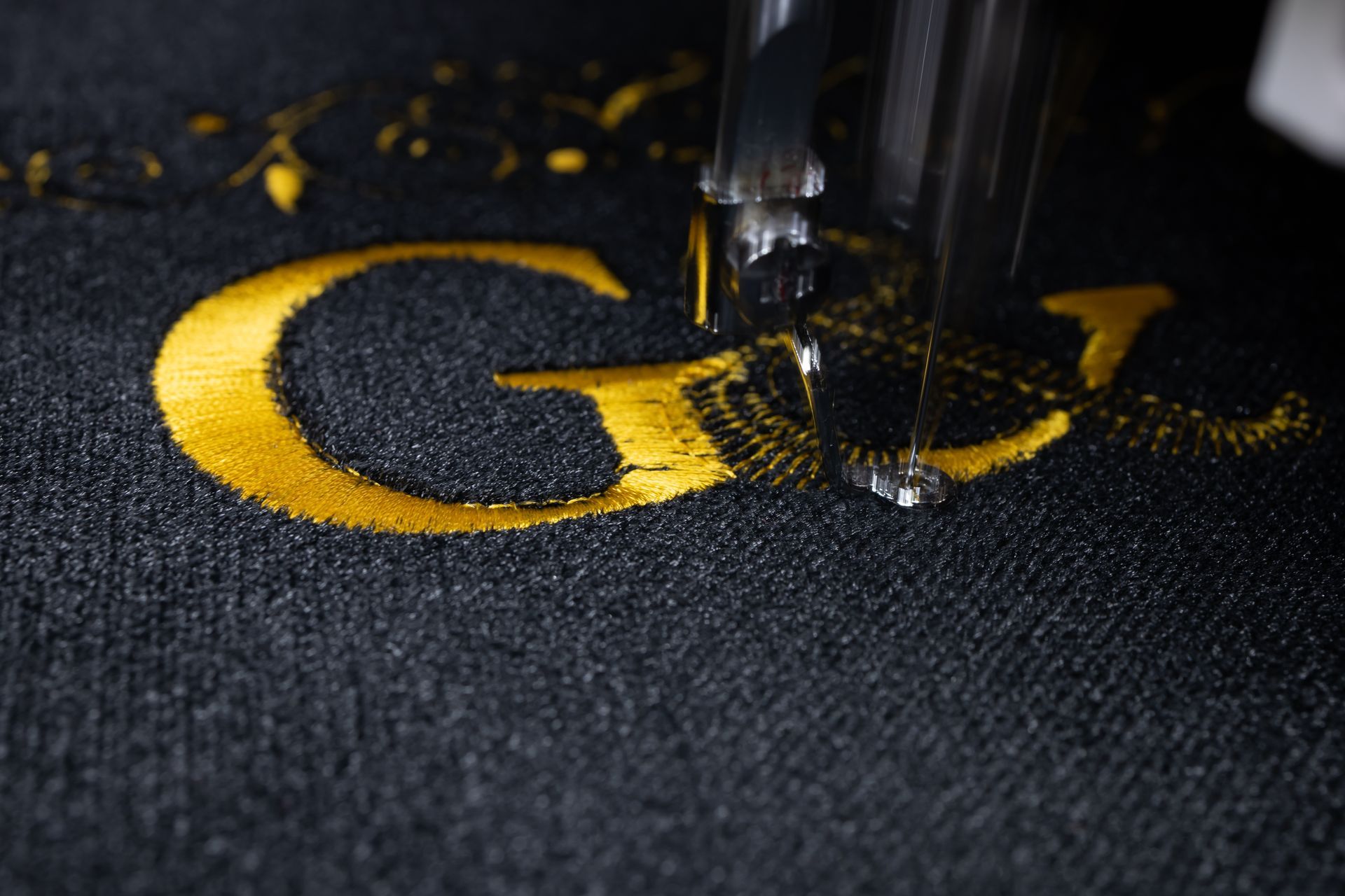 Close-up of a sewing machine embroidering the gold letters