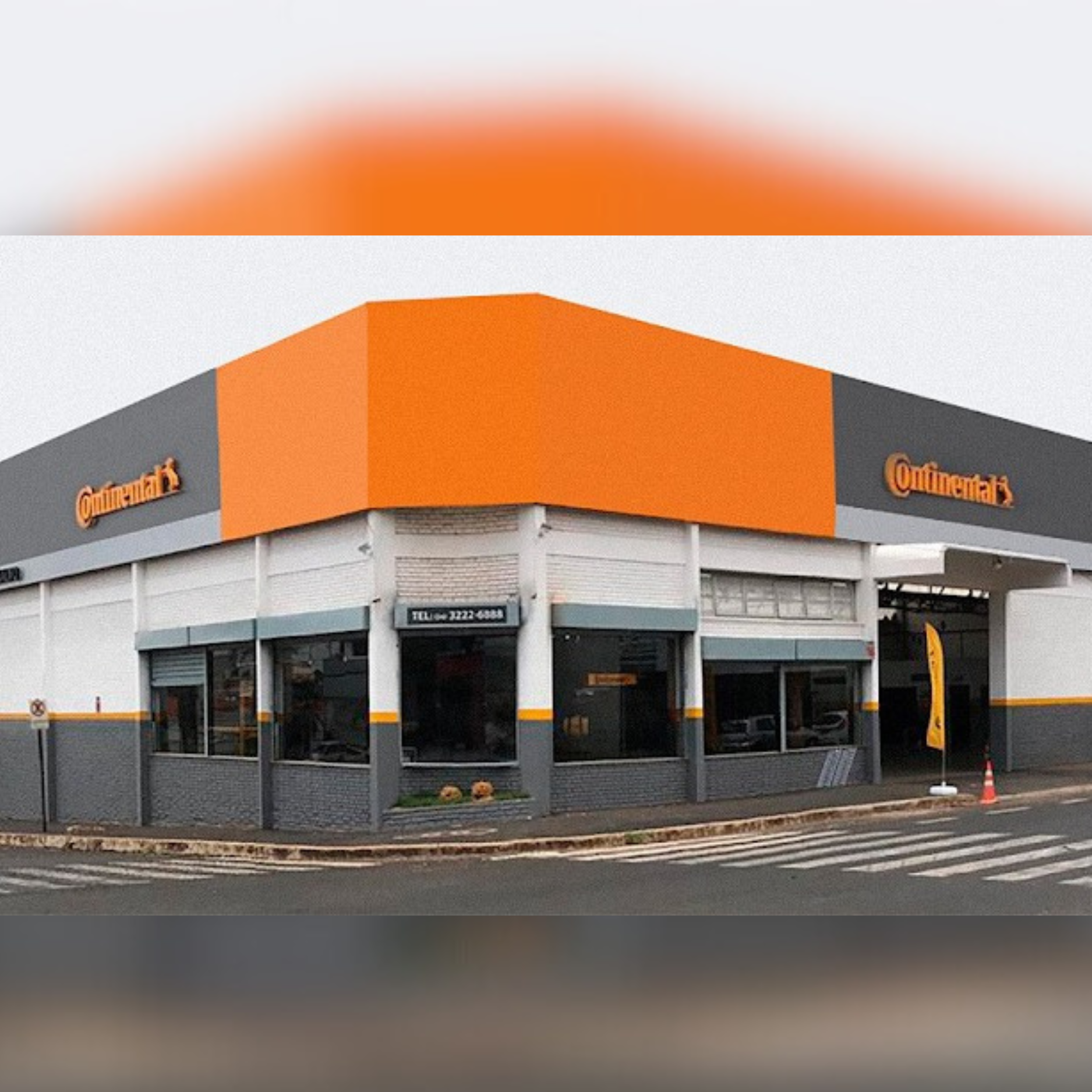 Fachada de uma loja de pneus Continental com sinalização laranja e cinza.
