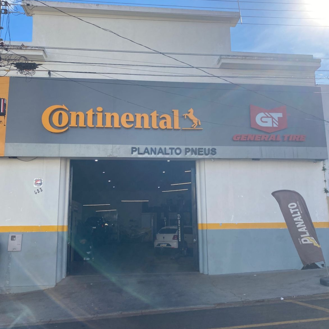 Loja de pneus Planato Pneus com logotipo da Continental e entrada da garagem aberta. Foto externa.