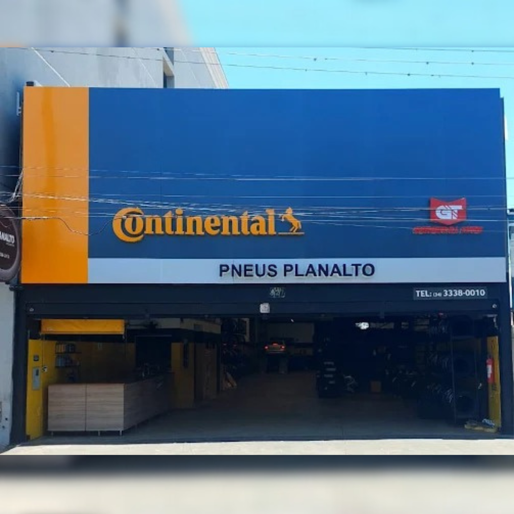 Fachada de loja de pneus Continental com placa azul e laranja. Nome 