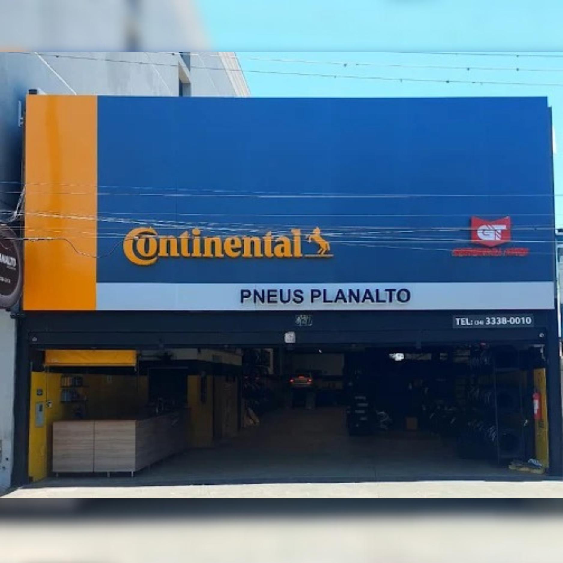 Fachada de loja de pneus Continental com placa azul e laranja. Nome 