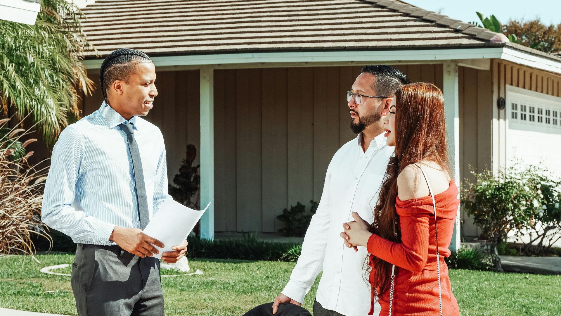 Real estate agent showing house to couple. Agent holding papers, discussing details.