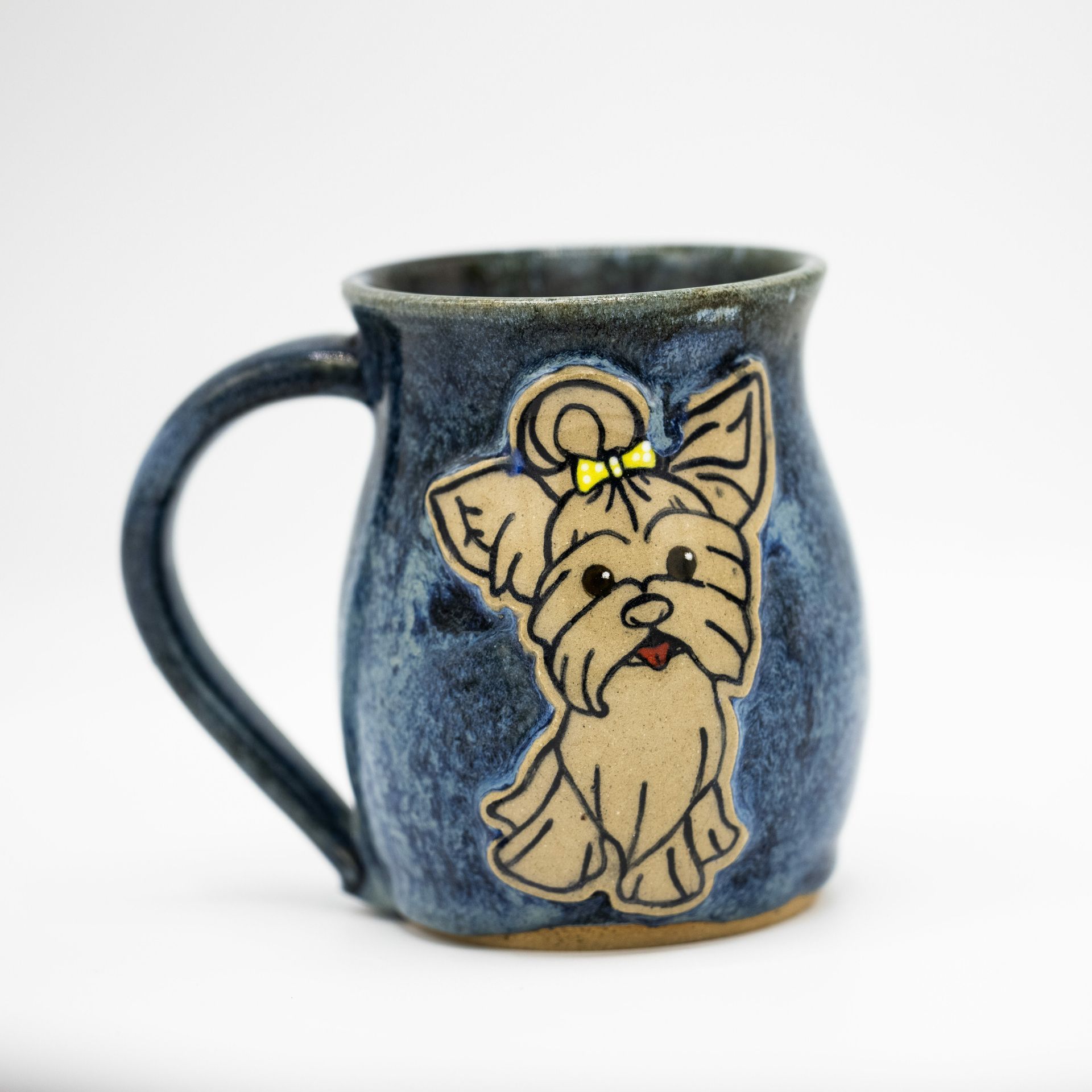 A blue, speckled ceramic mug with a sculpted tan Yorkie dog wearing a small yellow bow on its head.