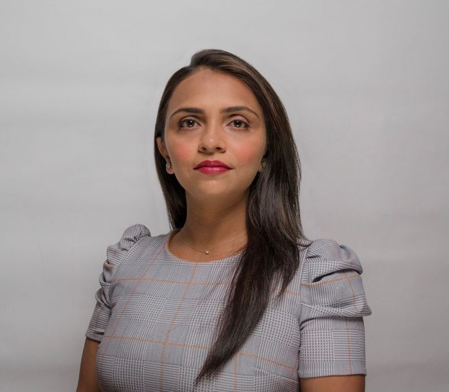 A woman with long hair is wearing a gray shirt and red lipstick.