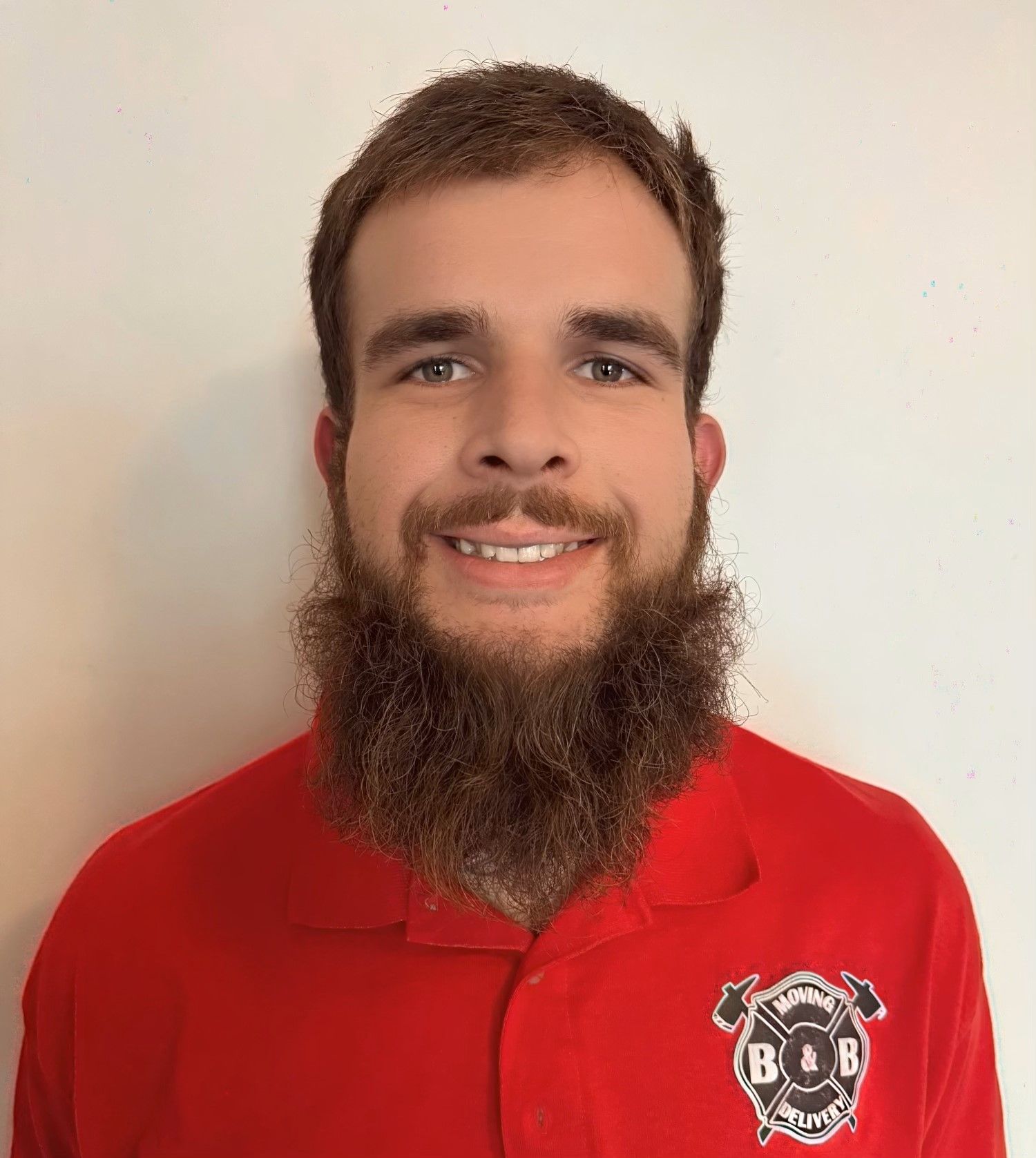 A man with a beard is wearing a red shirt with the letter b on it