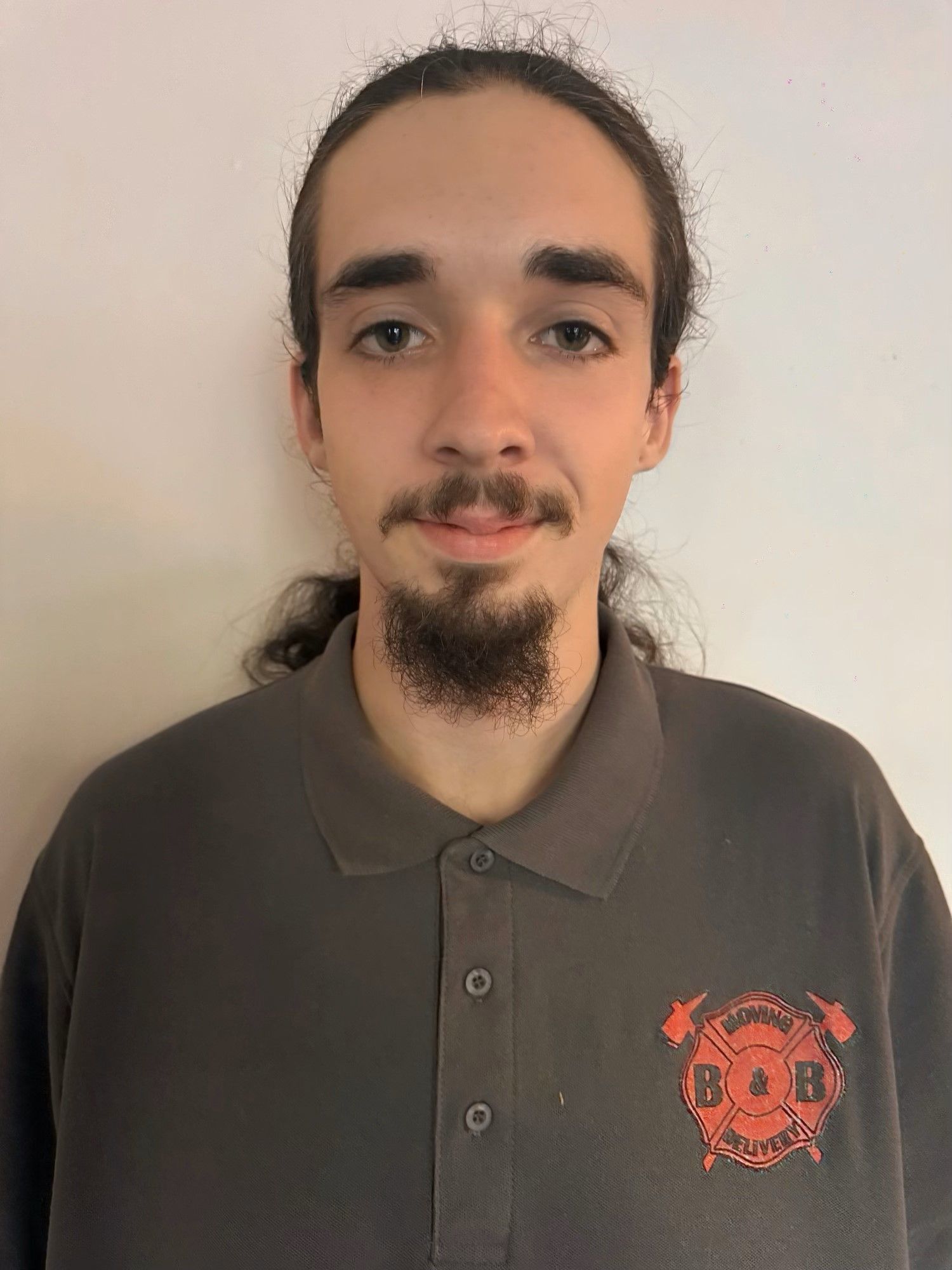 A man with a beard is wearing a grey polo shirt