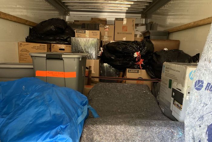 The inside of a moving truck filled with boxes and a blue tarp