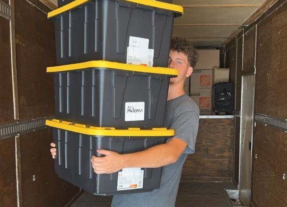 A man is carrying a stack of boxes in a truck.