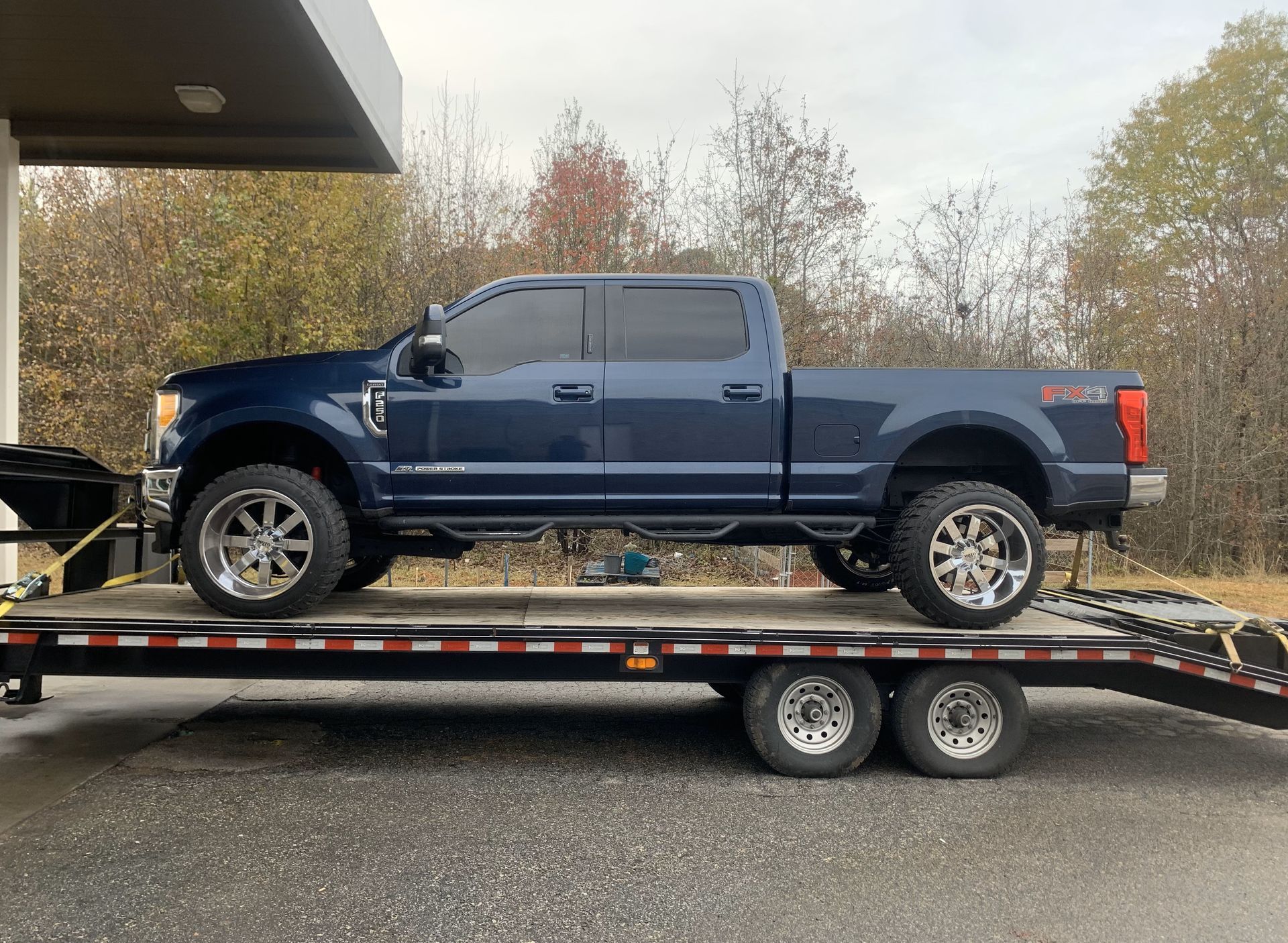 A blue truck is sitting on top of a trailer.