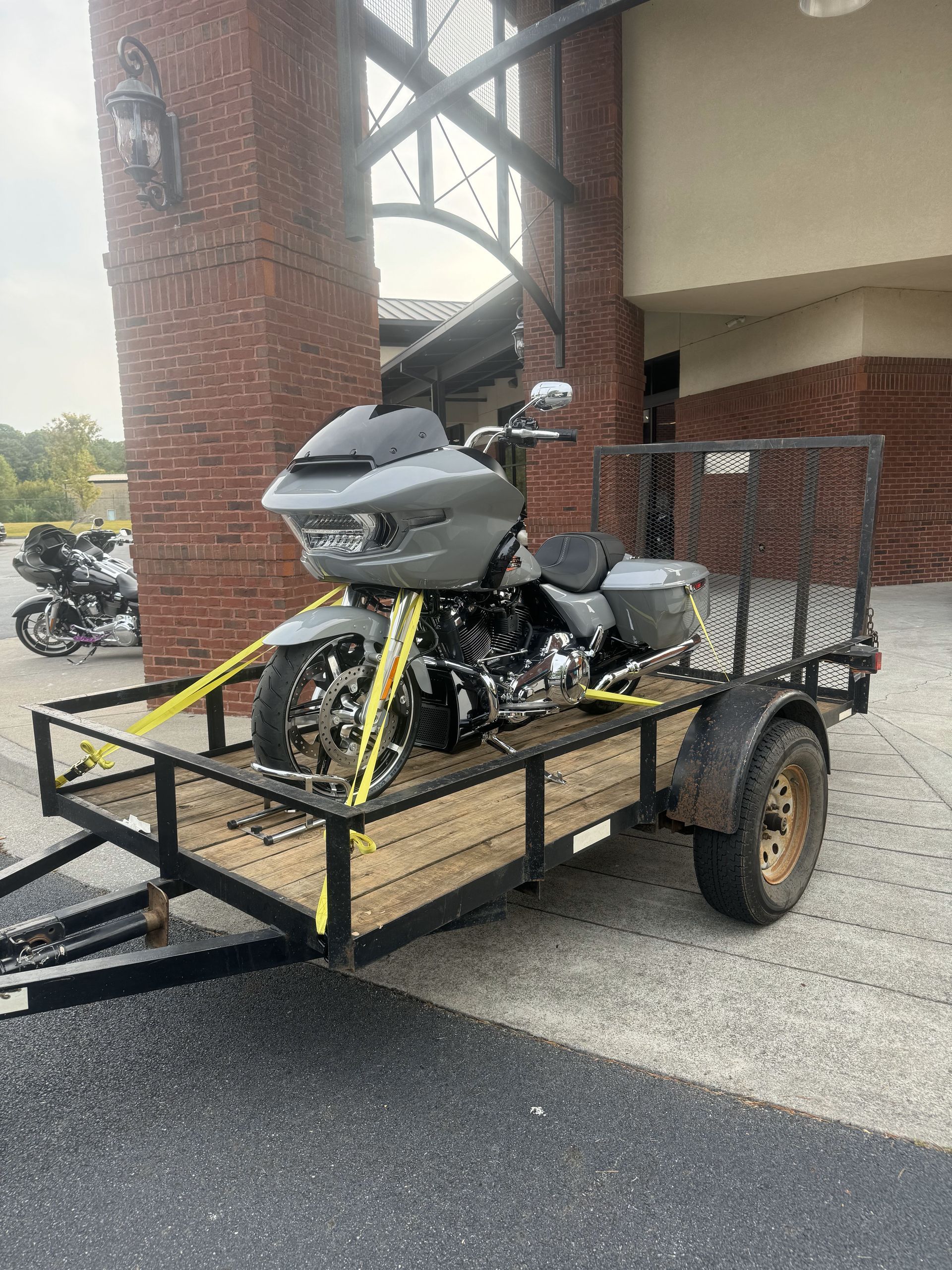 A motorcycle is sitting on a trailer in front of a building.