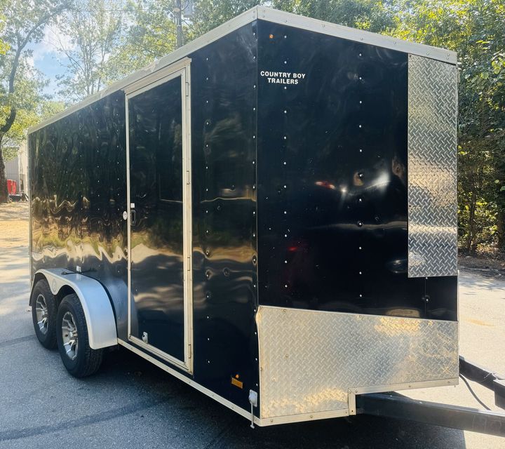 A black trailer is parked on the side of the road