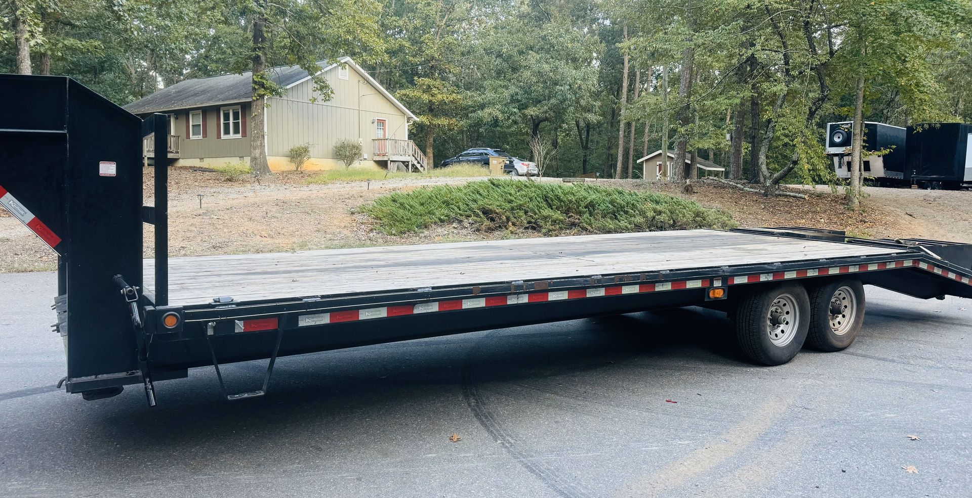 A flatbed trailer is parked on the side of the road