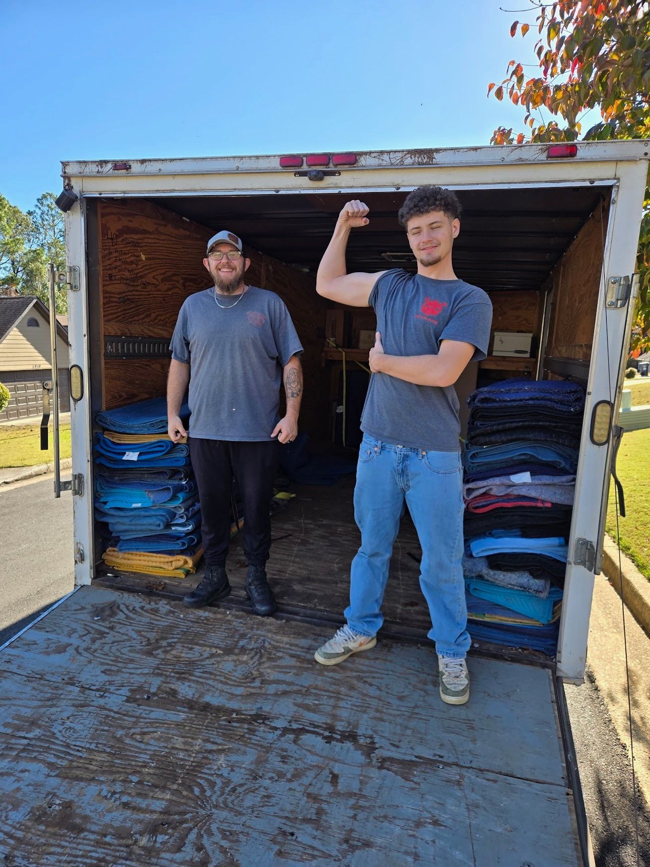 Two men are standing in front of a truck with a motorcycle in it.