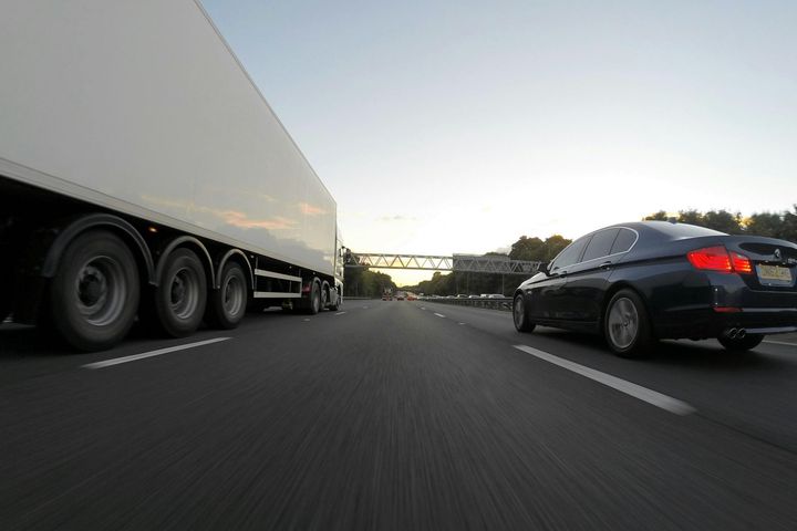 A car and a truck are driving down a highway