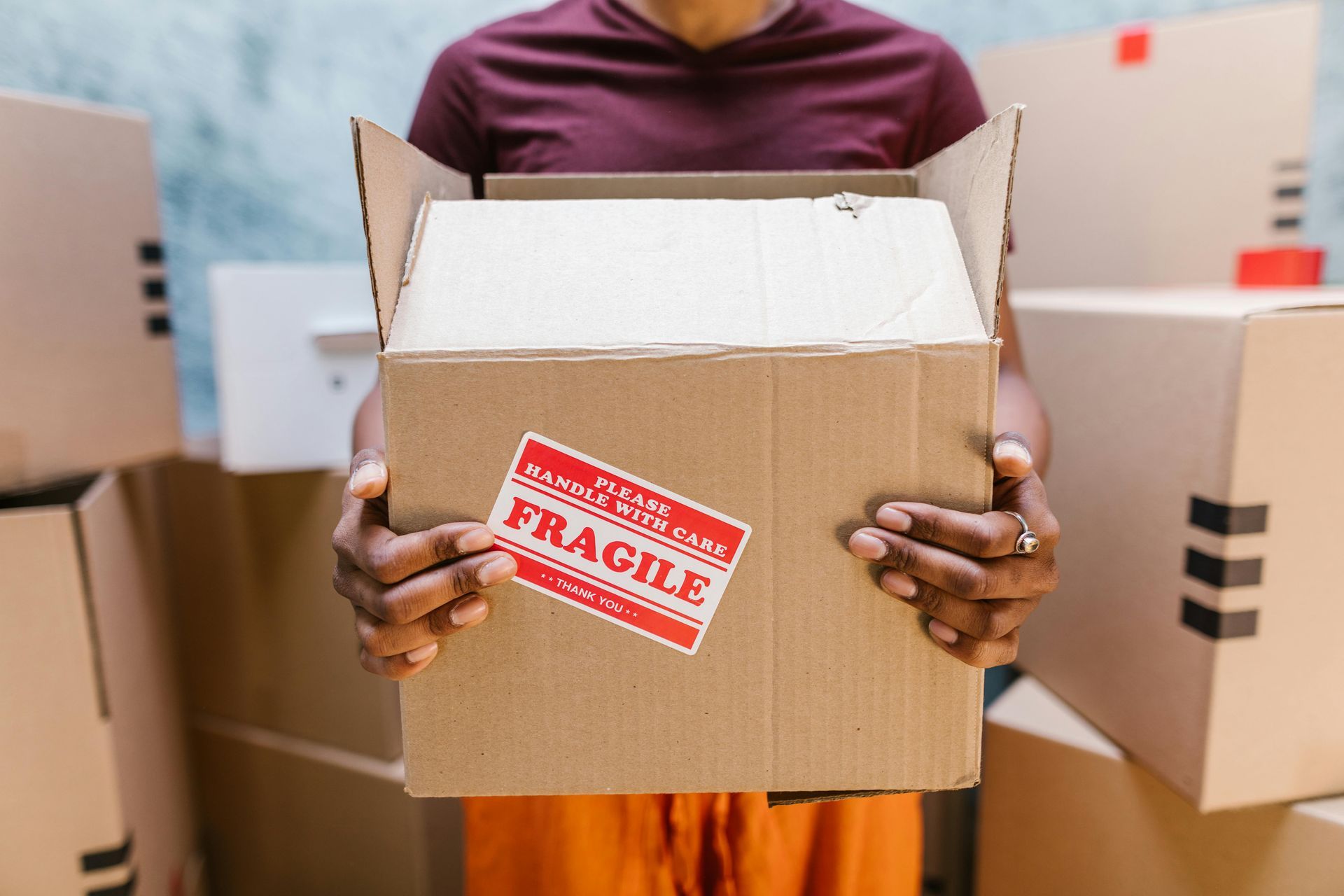 A person is holding a cardboard box with a fragile sticker on it