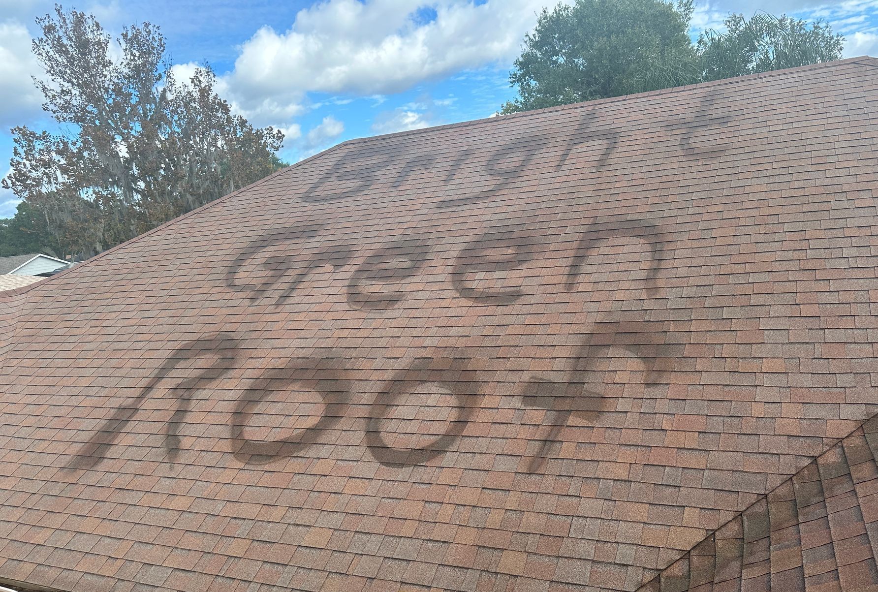 Happy Florida homeowner standing in front of a two-story house with a restored asphalt shingle roof.