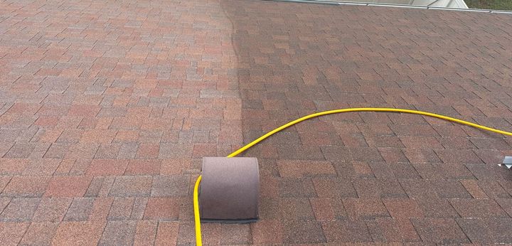 A roll of tape is sitting on a brick floor next to a yellow hose.