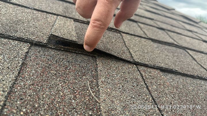 A person is pointing at a hole in a roof.