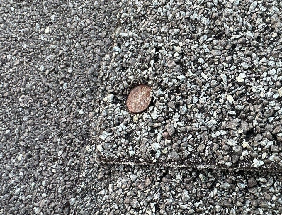 A penny is sitting on top of a pile of gravel.