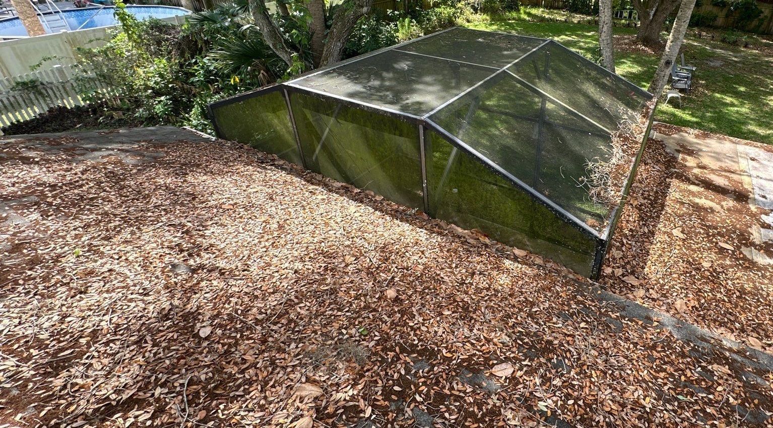 A greenhouse is sitting on top of a pile of leaves.