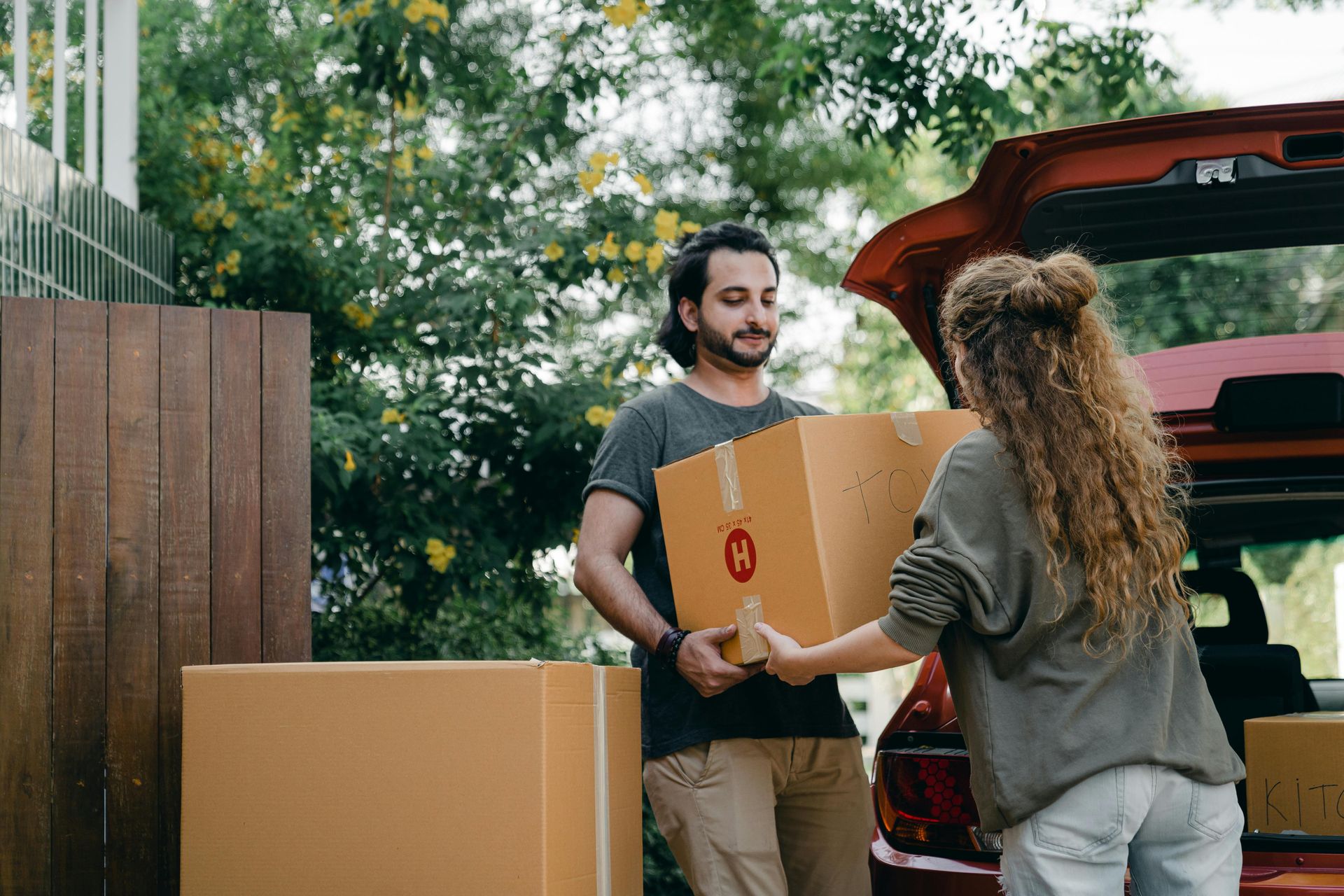 Man and woman loading moving boxes into vehicle during home relocation process
