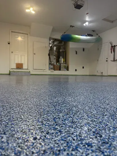 A clean garage featuring a blue and white speckled epoxy floor, a hanging kayak, and white interior doors.
