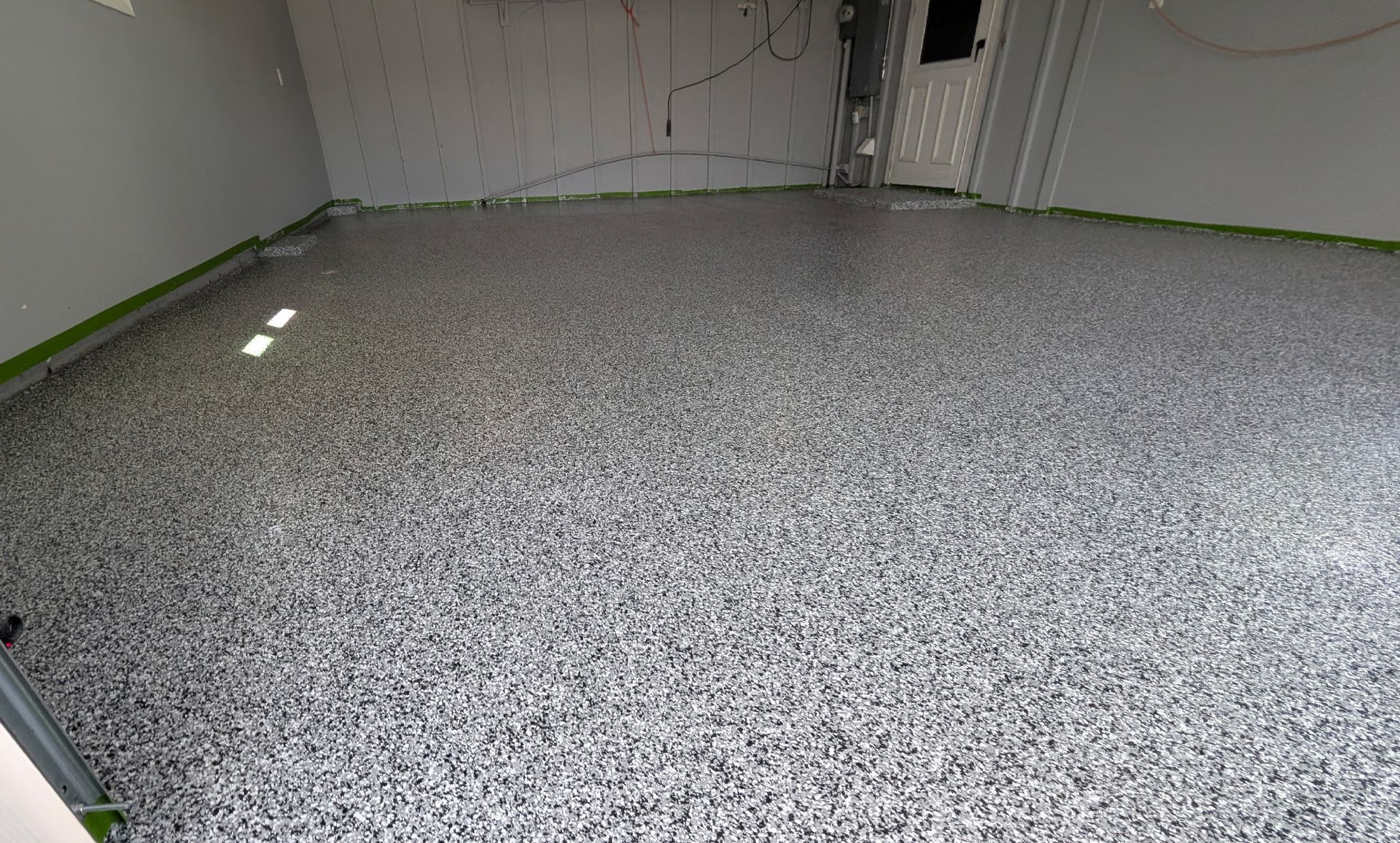 A freshly installed gray, black, and white speckled epoxy garage floor.