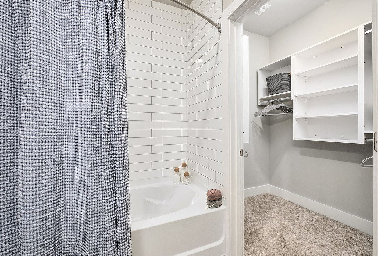 A bathroom with a bathtub and a walk in closet.