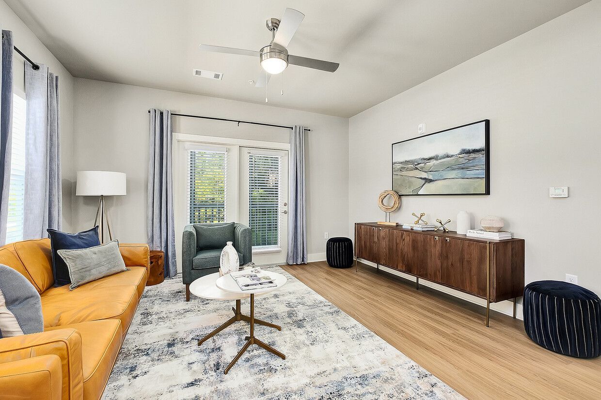 A living room with a couch , chair , table and ceiling fan.