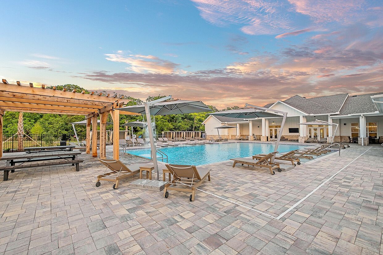 A large swimming pool surrounded by chairs and a pergola.