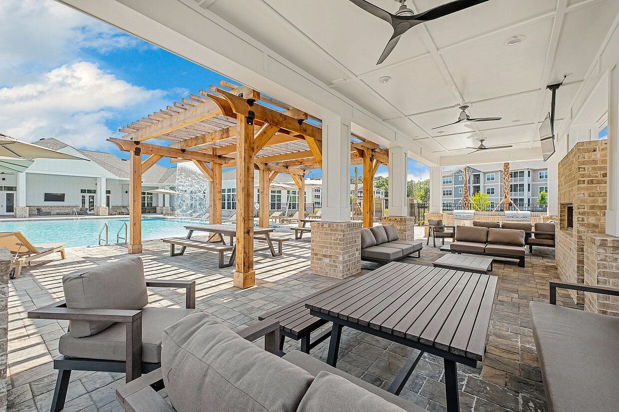 A patio area with tables and chairs next to a pool.