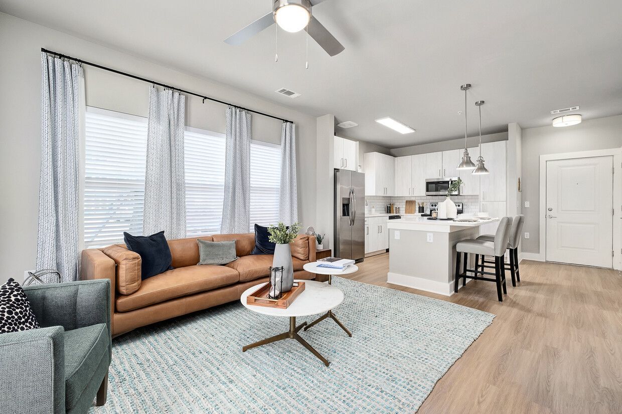 A living room with a couch , chair , coffee table and ceiling fan.