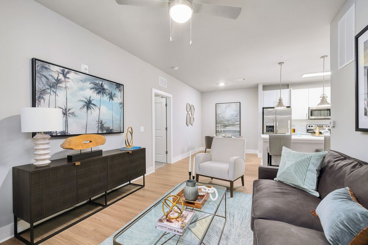 A living room with a couch , chair , coffee table and ceiling fan.