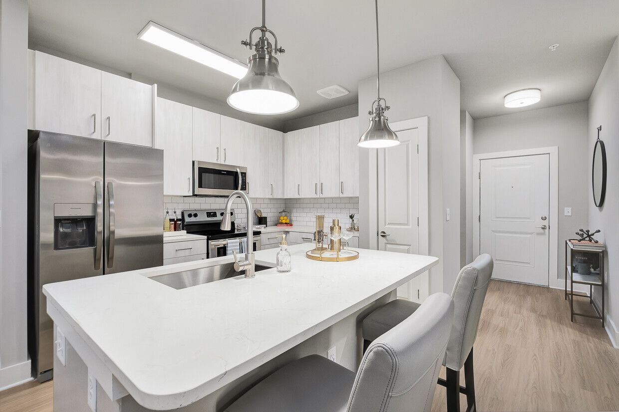 A kitchen with white cabinets , stainless steel appliances and a large island.